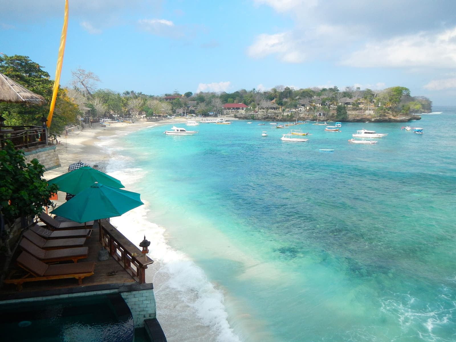 Clear turquoise water, a beach and moored boats at Mushroom Bay, Nusa Lembongan
